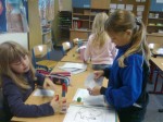 Jenny und Natalie bauen eine Brücke mit Steckwürfeln und Papier